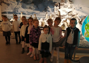 Dzieci stoją przy pingwinach